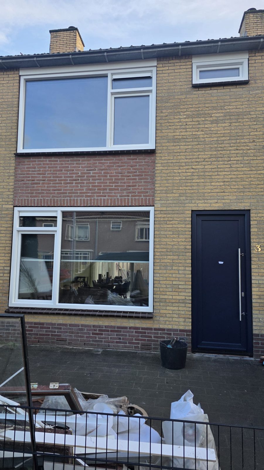 Wit kozijn met grote ruit en antraciet voordeur in een rijtjeswoning