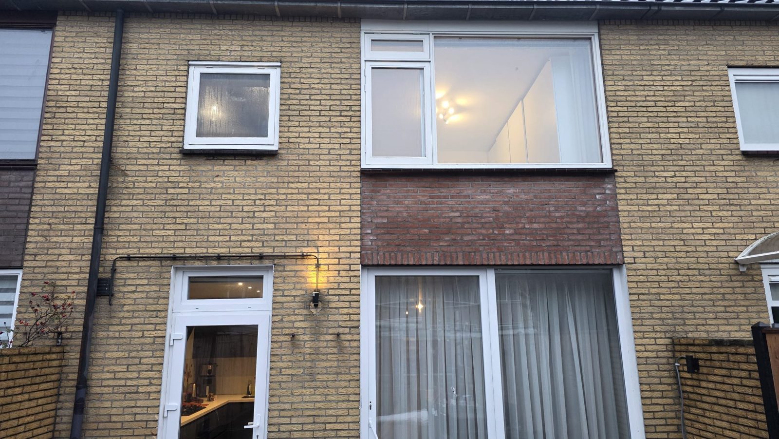 Voorgevel met vernieuwde kozijnen in de schemering